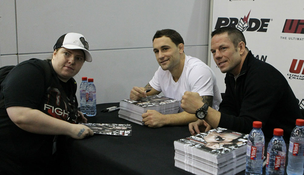 UFC Lightweight Champion Frankie Edgar (center) and UFC Welterweight fighter Marcus Davis (R) pose for a photo with a fan