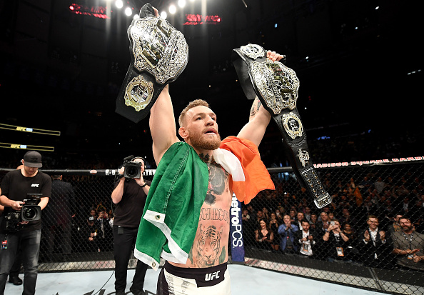 Conor McGregor celebrates with both of his belts after defeating Eddie Alvarez at UFC 205