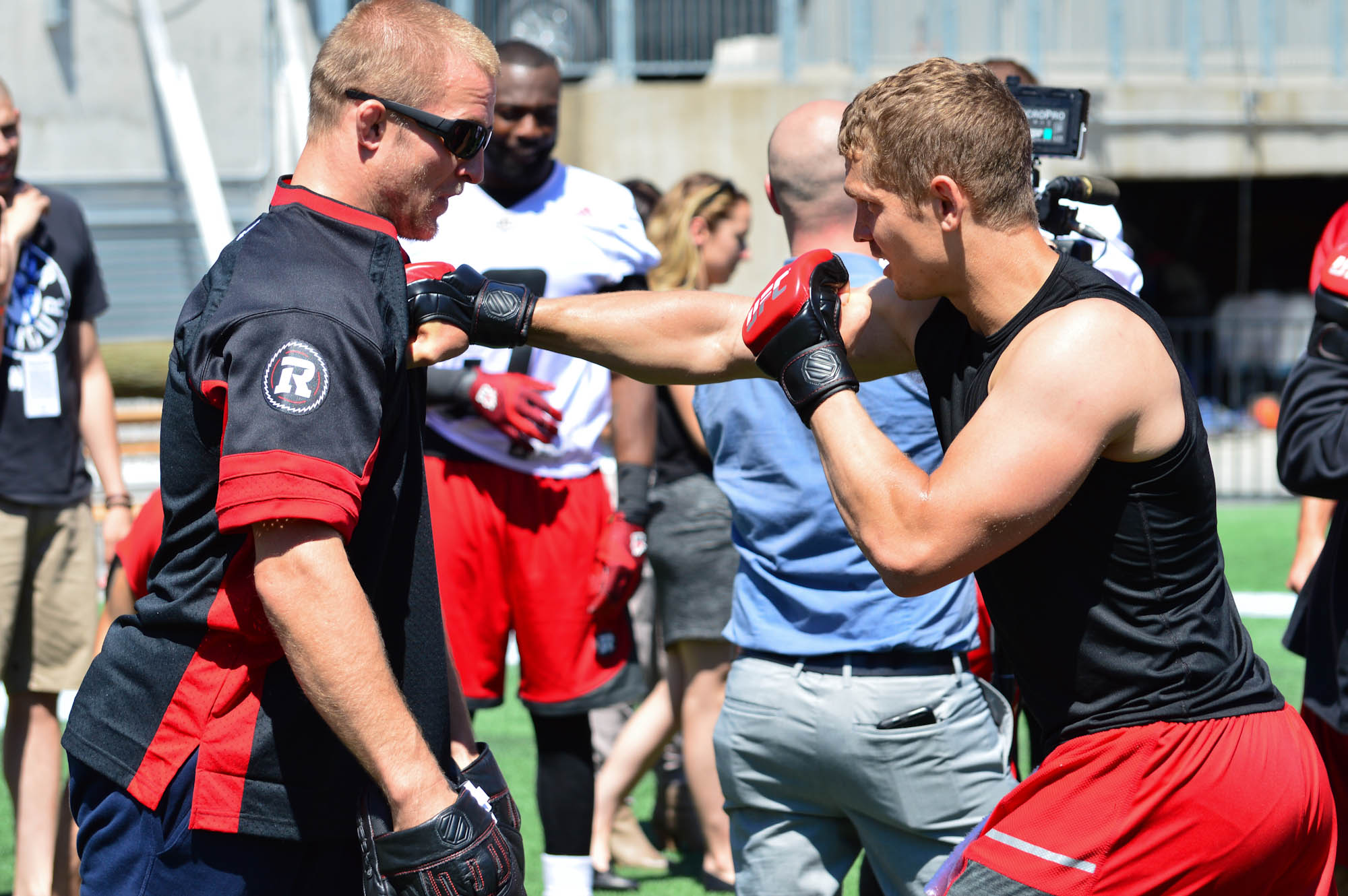 Misha Cirkunov (left) takes a punch from Ottawa Redblacks quarterback Trevor Harris during a training session on Wednesday, June 15 at The Stadium at TD Place. (John Barry/Zuffa LLC)