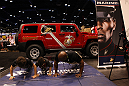 Two young fans do push-ups with at Marine at the United States Marine Corps booth at the UFC Fan Expo