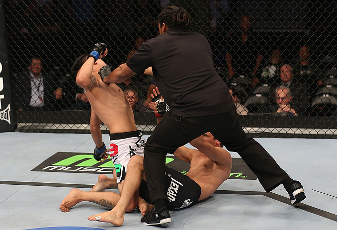 DENVER, CO - AUGUST 11: Referee Herb Dean steps in to stop the bout as Erik Perez (L) knocks out Ken Stone during their bantamweight bout at UFC 150 inside Pepsi Center on August 11, 2012 in Denver, Colorado. (Photo by Nick Laham/Zuffa LLC/Zuffa LLC via Getty Images)