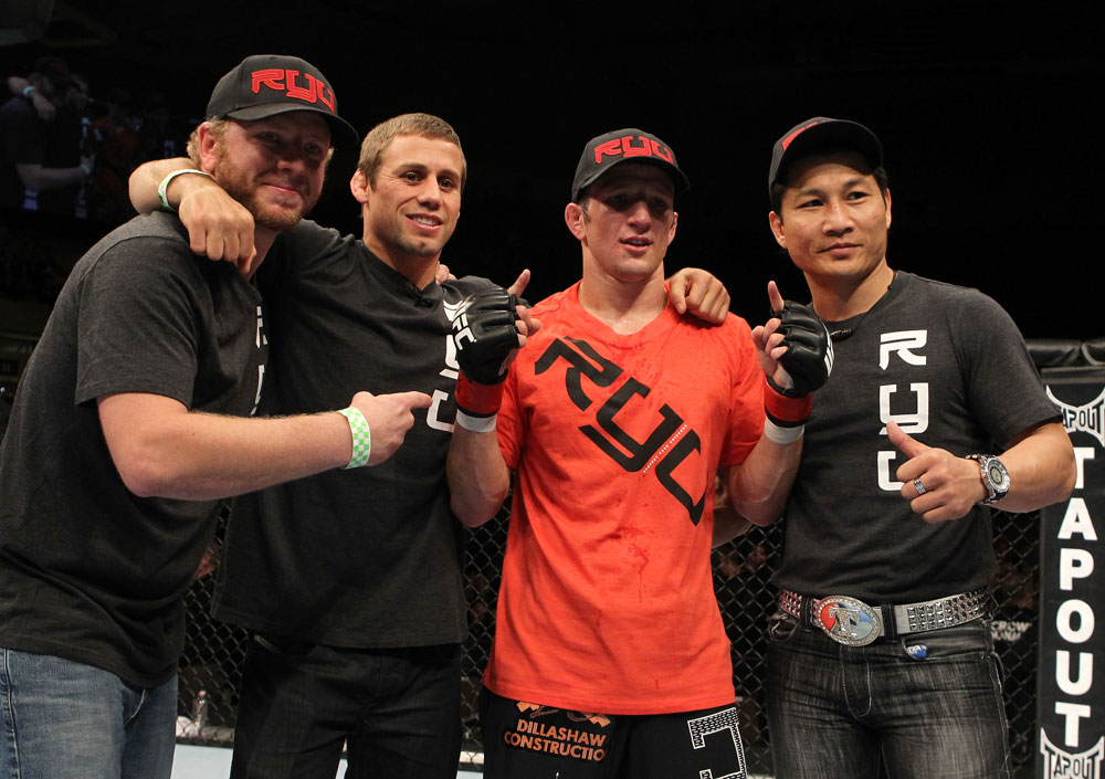 OMAHA, NE - FEBRUARY 15:  TJ Dillashaw (orange shirt) poses for a photo with his team after defeating Walel Watson during the UFC on FUEL TV event at Omaha Civic Auditorium on February 15, 2012 in Omaha, Nebraska.  (Photo by Josh Hedges/Zuffa LLC/Zuffa LLC via Getty Images) *** Local Caption *** TJ Dillashaw; Urijah Faber