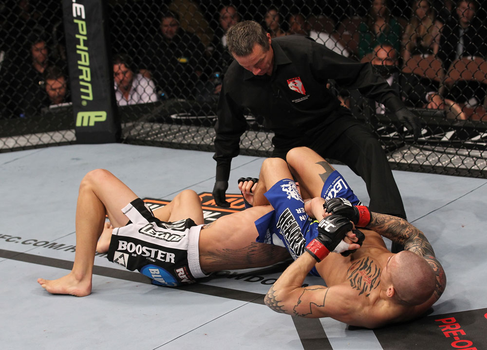 LAS VEGAS, NV - FEBRUARY 04:  Dustin Poirier (right) attempts to submit Max Holloway as referee Steve Mazzagatti looks on during the UFC 143 event at Mandalay Bay Events Center on February 4, 2012 in Las Vegas, Nevada.  (Photo by Nick Laham/Zuffa LLC/Zuffa LLC via Getty Images) *** Local Caption *** Dustin Poirier; Steve Mazzagatti