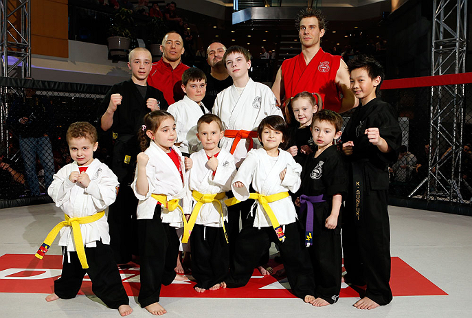MONTREAL, QC - MARCH 13: UFC welterweight champion Georges St-Pierre poses for photos with students of the Sunfuki Karate school during the UFC 158 open workouts at Complexe Desjardins on March 13, 2013 in Montreal, Quebec, Canada. (Photo by Josh Hedges/Zuffa LLC/Zuffa LLC via Getty Images)