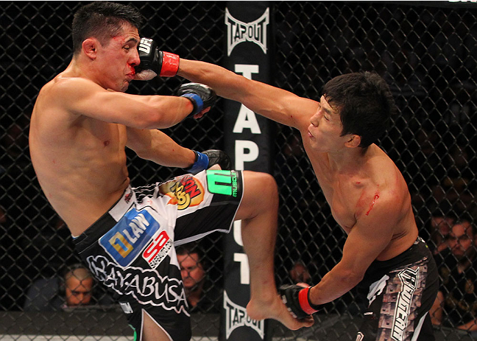 INDIANAPOLIS, IN - AUGUST 28:  (R-L) Takeya Mizugaki punches Erik Perez in their bantamweight fight during the UFC on FOX Sports 1 event at Bankers Life Fieldhouse on August 28, 2013 in Indianapolis, Indiana. (Photo by Ed Mulholland/Zuffa LLC/Zuffa LLC via Getty Images)