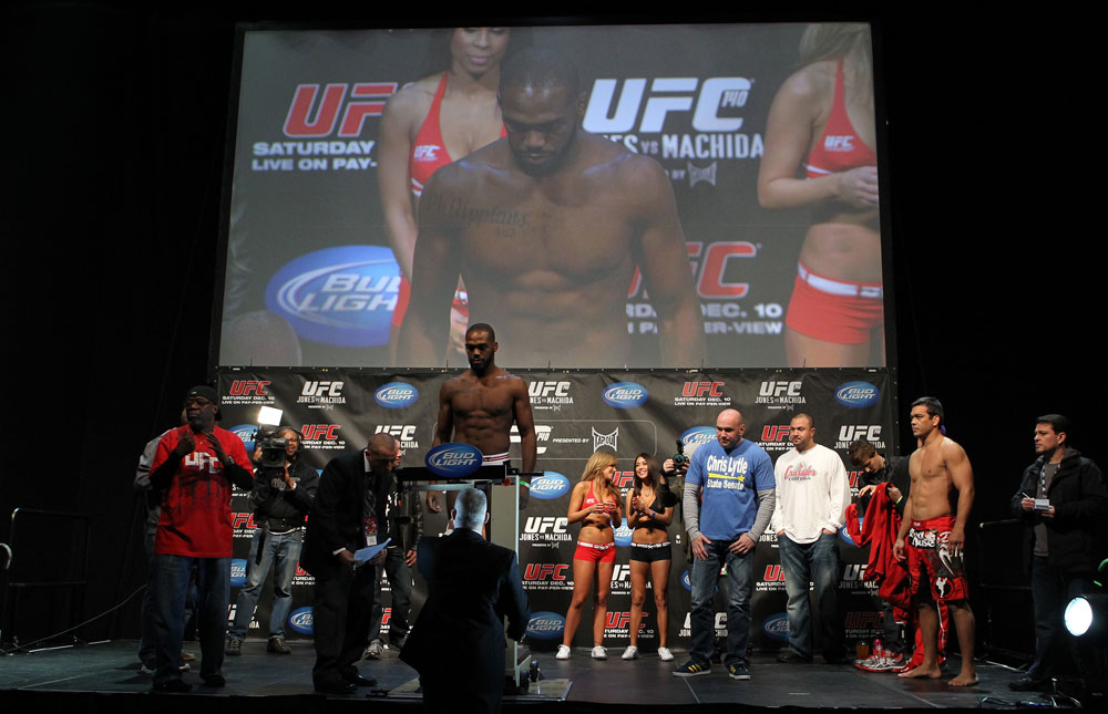 TORONTO, ON - DECEMBER 09:  UFC Light Heavyweight Champion Jon "Bones" Jones weighs in as opponent Lyoto Machida (red shorts) looks on during the UFC 140 Official Weigh-in at the Air Canada Centre on December 9, 2011 in Toronto, Canada.  (Photo by Josh Hedges/Zuffa LLC/Zuffa LLC via Getty Images)