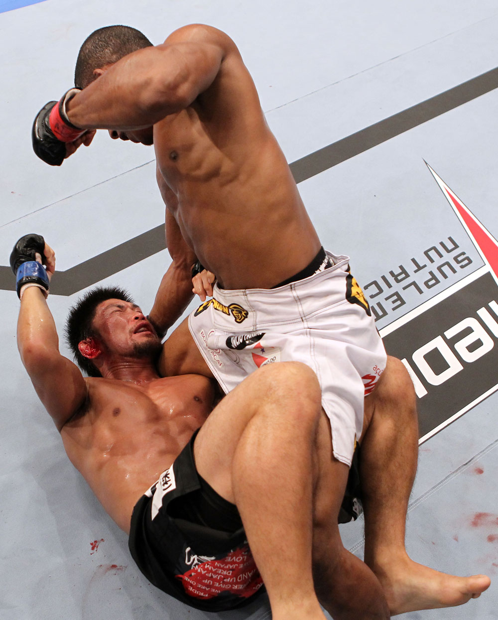 RIO DE JANEIRO, BRAZIL - JANUARY 14: Yuri Alcantara (Top) punches on top of Michihiro Omigawa (Bottom) in a featherweight bout during UFC 142 at HSBC Arena on January 14, 2012 in Rio de Janeiro, Brazil. (Photo by Josh Hedges/Zuffa LLC/Zuffa LLC via Getty Images)