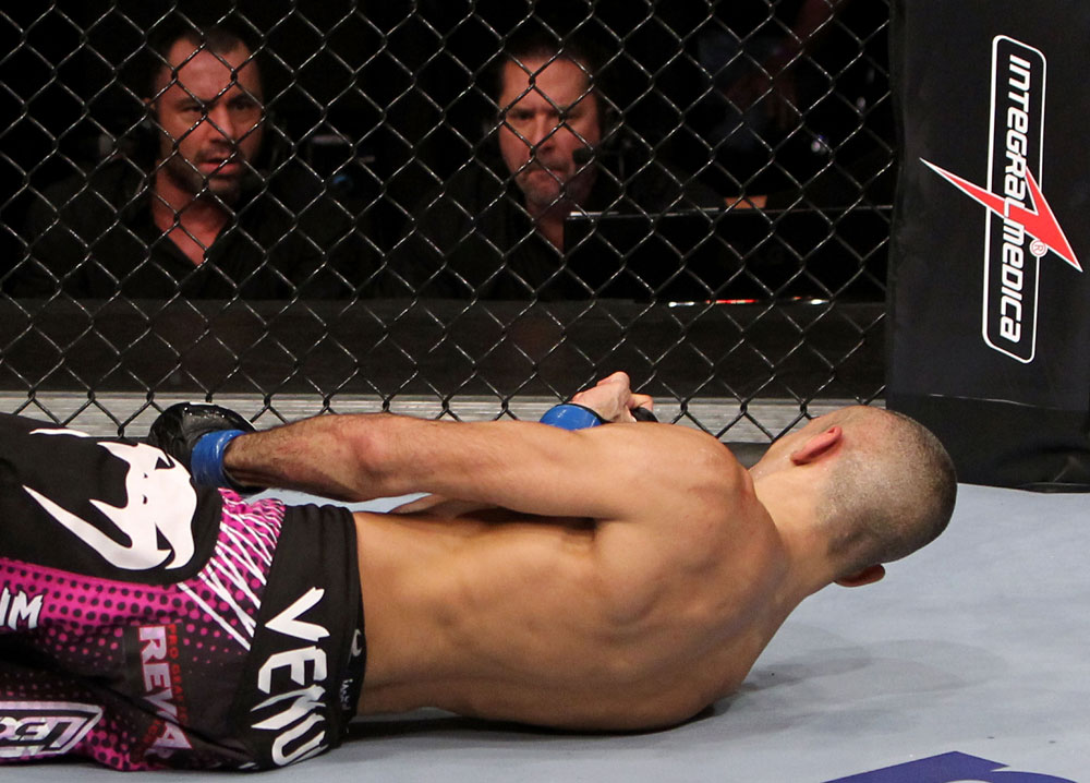 RIO DE JANEIRO, BRAZIL - JANUARY 14: Commentators Mike Goldberg (Top Right) and Joe Rogan (Top Left) look on as Terry Etim (Bottom) lays knocked out after being kicked by Edson Barboza (not pictured) with a spinning back kick in a lightweight bout during UFC 142 at HSBC Arena on January 14, 2012 in Rio de Janeiro, Brazil. (Photo by Josh Hedges/Zuffa LLC/Zuffa LLC via Getty Images)